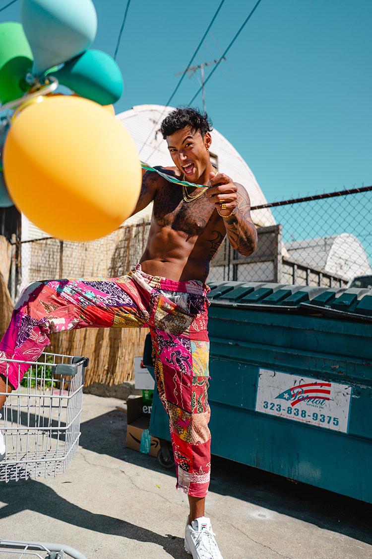 Topless man throwing balloons toward camera